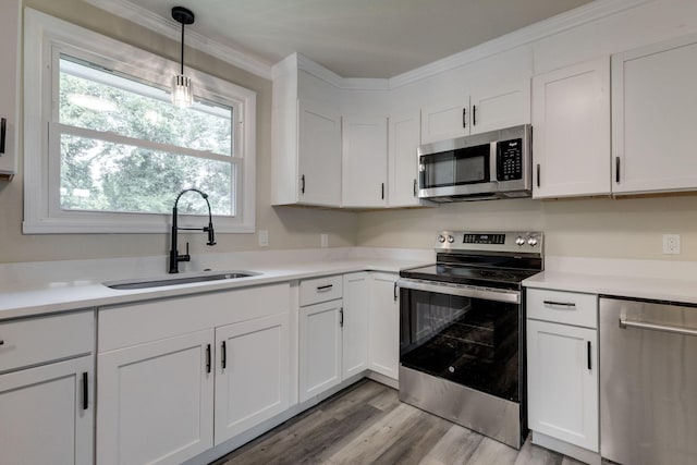 kitchen featuring white cabinets, sink, light hardwood / wood-style flooring, appliances with stainless steel finishes, and decorative light fixtures