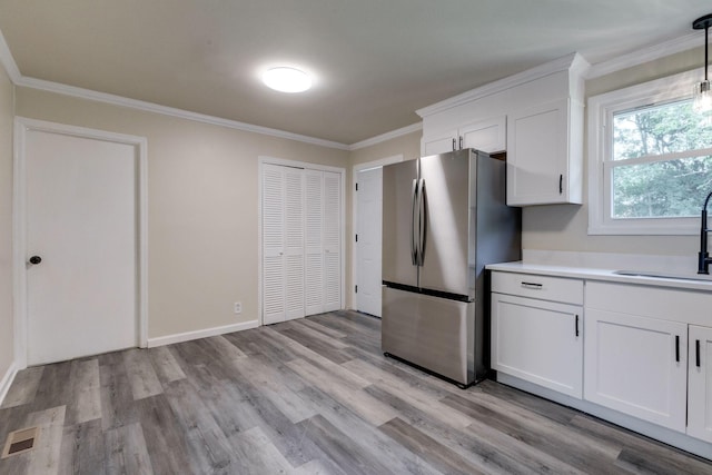 kitchen featuring ornamental molding, sink, decorative light fixtures, white cabinets, and stainless steel refrigerator