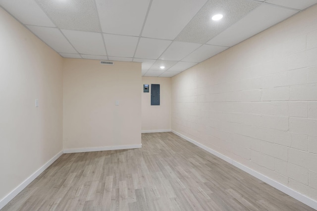 empty room featuring electric panel, a drop ceiling, and light hardwood / wood-style flooring