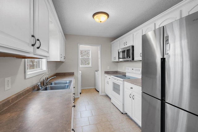 kitchen featuring white cabinets, washer and dryer, sink, and stainless steel appliances