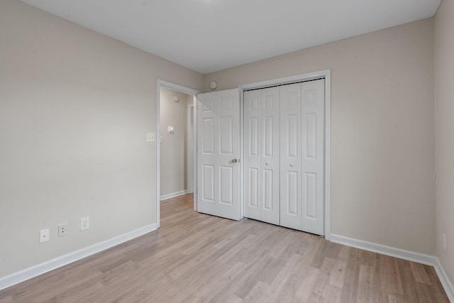 unfurnished bedroom with light hardwood / wood-style flooring and a closet