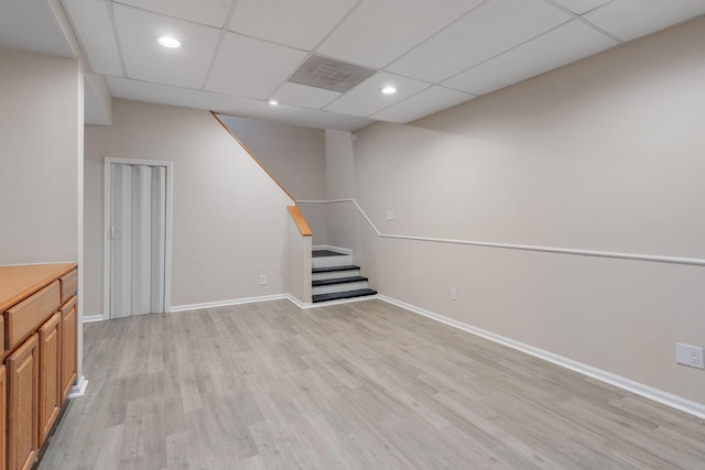 basement with a paneled ceiling and light hardwood / wood-style flooring