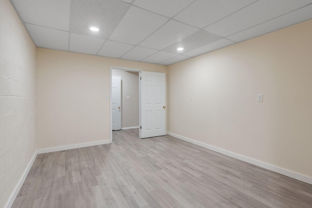 empty room with a paneled ceiling and light hardwood / wood-style floors