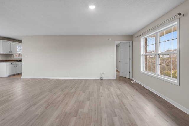 unfurnished living room featuring a textured ceiling and light wood-type flooring