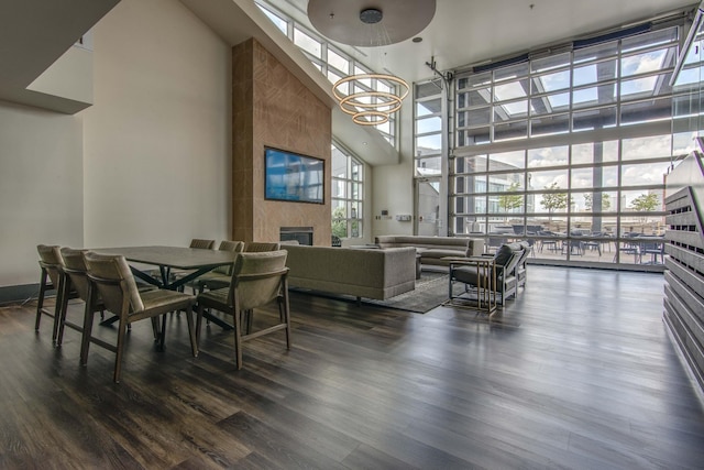 dining room featuring a fireplace, dark hardwood / wood-style flooring, a towering ceiling, and floor to ceiling windows