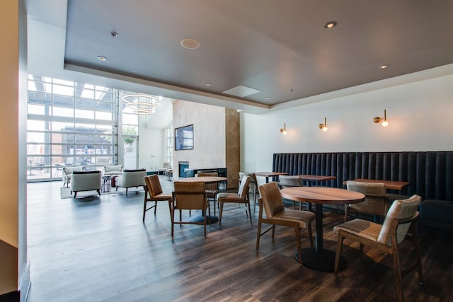 dining space with expansive windows, wood-type flooring, a tile fireplace, and a tray ceiling