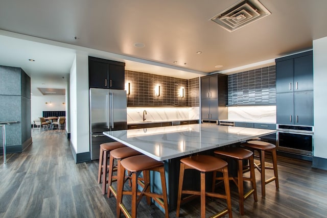 kitchen with a large island, a breakfast bar, stainless steel appliances, and dark hardwood / wood-style floors