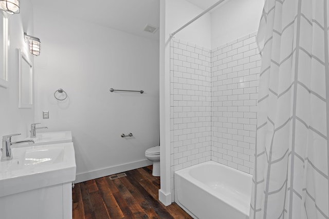 full bathroom featuring hardwood / wood-style floors, vanity, shower / bath combination with curtain, and toilet