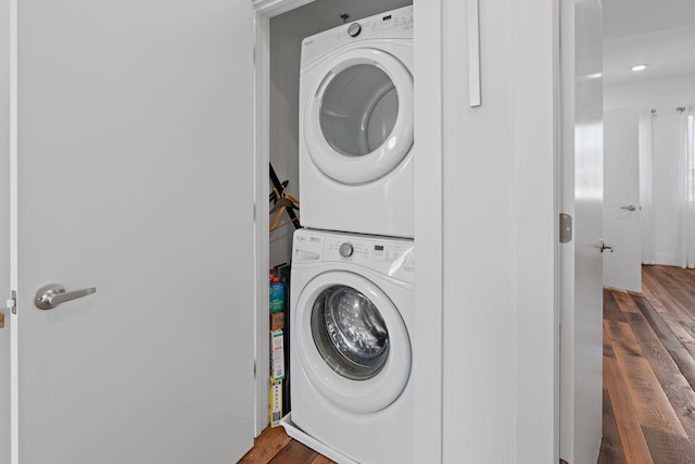 clothes washing area featuring dark wood-type flooring and stacked washer and clothes dryer