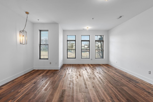 empty room featuring a notable chandelier and dark hardwood / wood-style flooring