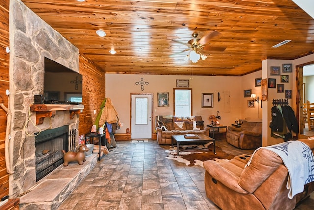 living room featuring ceiling fan, wooden ceiling, and a stone fireplace