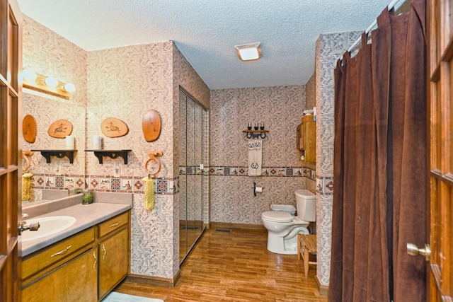 bathroom featuring toilet, hardwood / wood-style flooring, a textured ceiling, and vanity