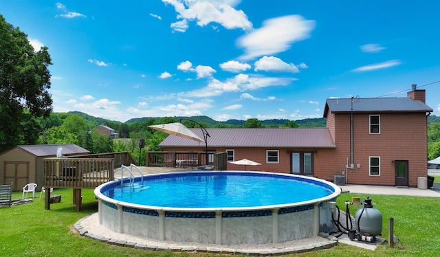 view of swimming pool featuring a storage shed, central AC, a yard, and a wooden deck