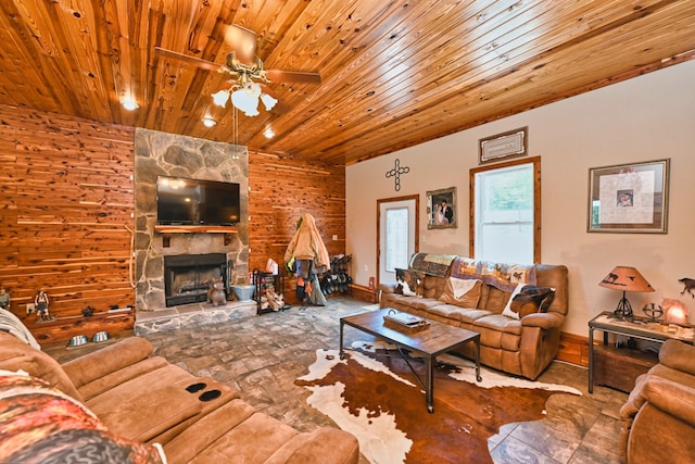 living room featuring wooden ceiling, wood walls, ceiling fan, and a fireplace