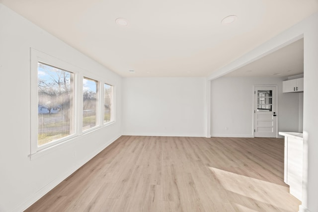 empty room with a wealth of natural light and light hardwood / wood-style floors