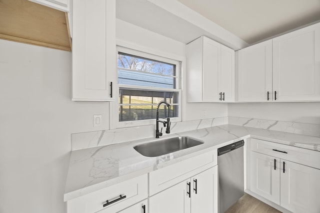 kitchen featuring sink, stainless steel dishwasher, light stone countertops, light hardwood / wood-style floors, and white cabinetry