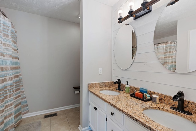 bathroom with a textured ceiling, vanity, tile patterned floors, and wood walls