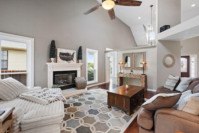 living room featuring ceiling fan, a towering ceiling, and dark wood-type flooring