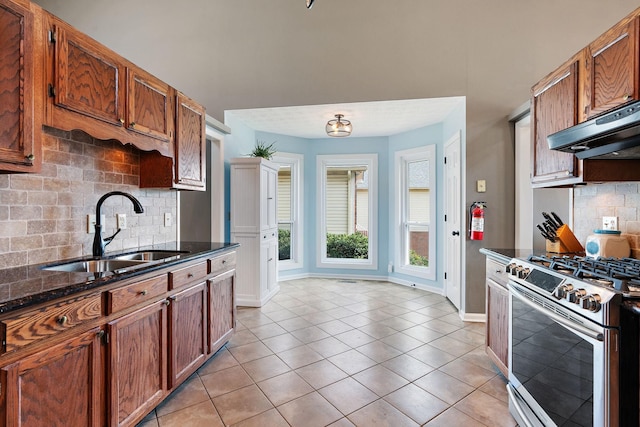 kitchen with stainless steel gas stove, decorative backsplash, sink, and light tile patterned floors