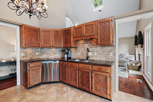 kitchen with an inviting chandelier, sink, stainless steel dishwasher, tasteful backsplash, and light tile patterned flooring