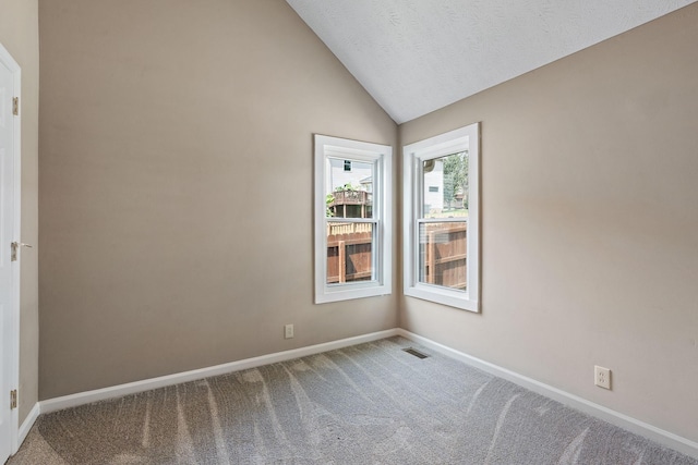 carpeted empty room with a textured ceiling and vaulted ceiling