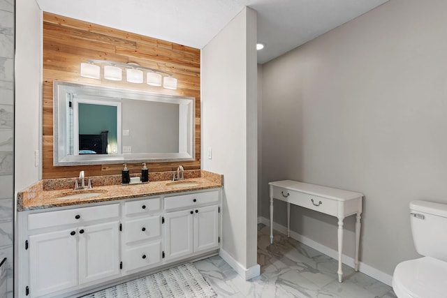 bathroom featuring vanity, wood walls, and toilet