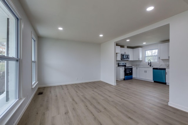 kitchen with white cabinets, light hardwood / wood-style floors, sink, and appliances with stainless steel finishes