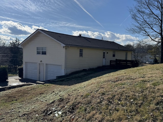 view of side of home featuring a lawn and a garage