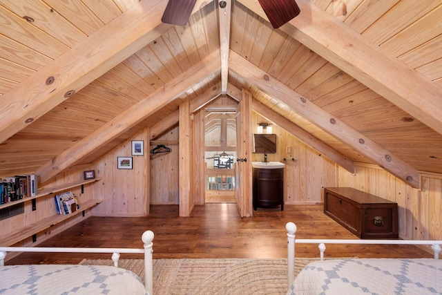 unfurnished bedroom featuring hardwood / wood-style floors, lofted ceiling with beams, ensuite bathroom, and wood walls