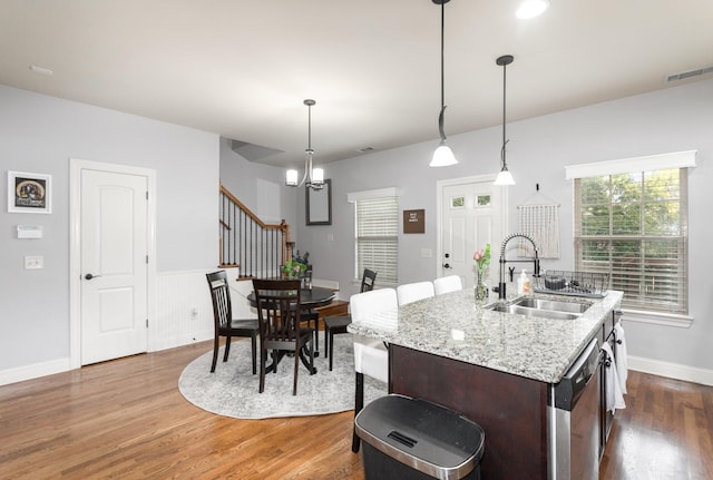 kitchen featuring pendant lighting, a kitchen island with sink, sink, stainless steel dishwasher, and dark hardwood / wood-style flooring