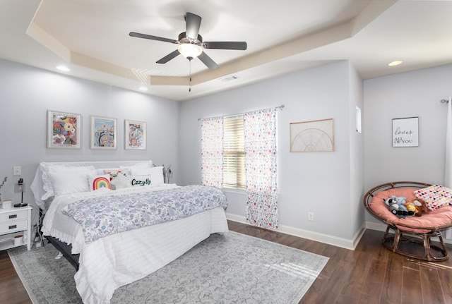 bedroom with a tray ceiling, ceiling fan, and dark hardwood / wood-style floors