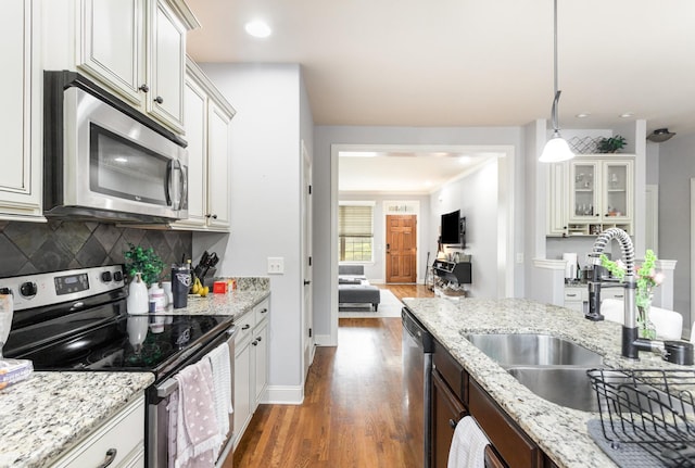 kitchen featuring decorative backsplash, appliances with stainless steel finishes, sink, decorative light fixtures, and white cabinetry