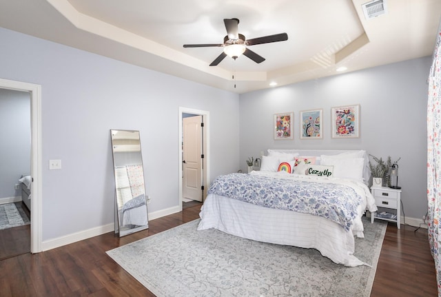 bedroom with a tray ceiling, ceiling fan, and dark hardwood / wood-style floors