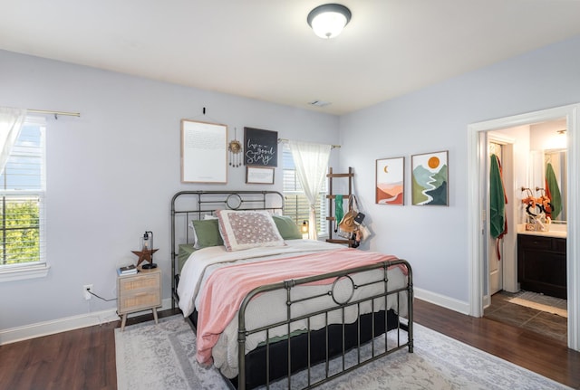 bedroom with ensuite bathroom and dark wood-type flooring