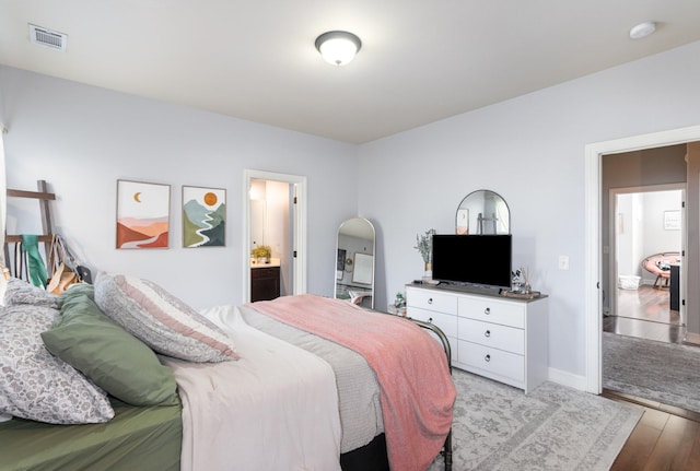 bedroom with light wood-type flooring and connected bathroom