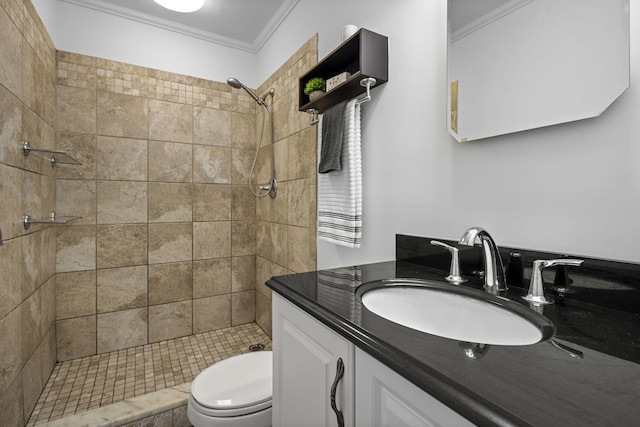 bathroom with tiled shower, crown molding, vanity, and toilet