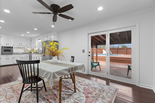 dining area featuring ceiling fan, dark wood-type flooring, and sink