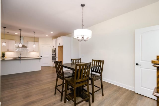 dining space featuring sink, dark wood-type flooring, and an inviting chandelier