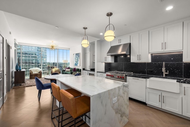 kitchen featuring parquet floors, dark stone counters, stainless steel range, sink, and decorative light fixtures