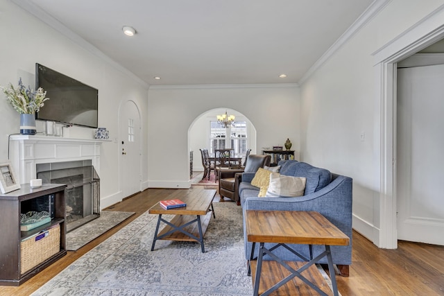 living room with hardwood / wood-style flooring, an inviting chandelier, and ornamental molding