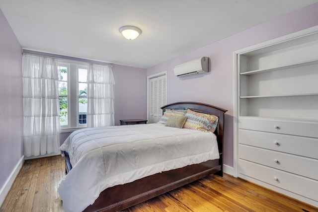 bedroom with a closet, light hardwood / wood-style floors, and a wall mounted AC