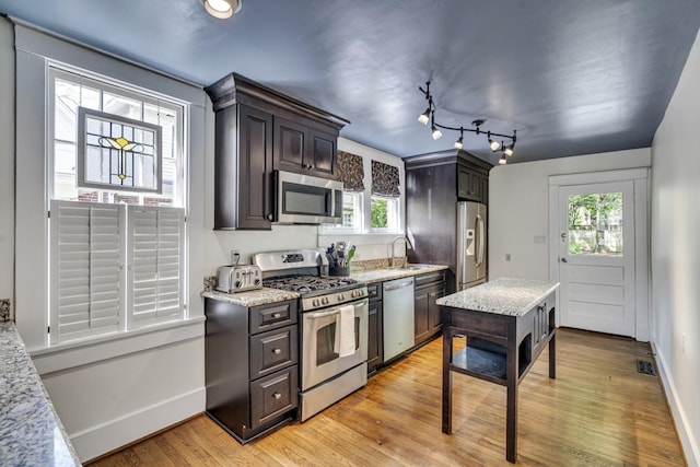 kitchen with light hardwood / wood-style floors, dark brown cabinetry, stainless steel appliances, and a wealth of natural light