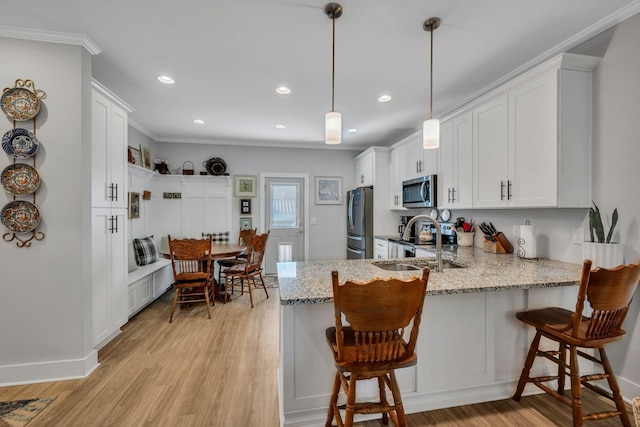 kitchen with white cabinets, pendant lighting, sink, and appliances with stainless steel finishes