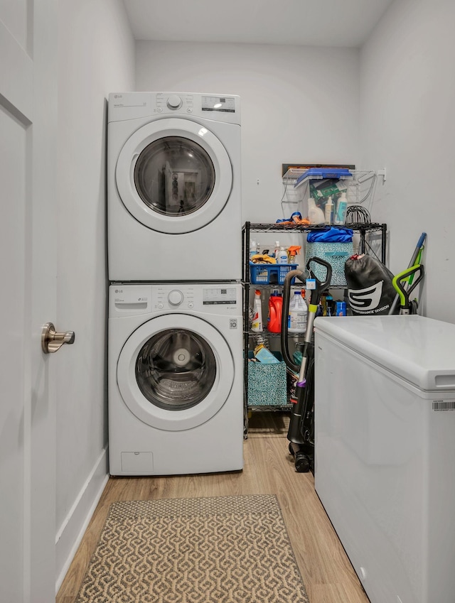 laundry area with stacked washer and dryer and light hardwood / wood-style floors