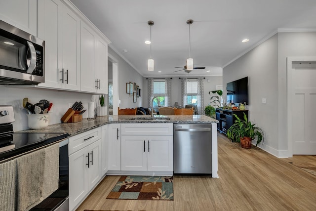 kitchen with kitchen peninsula, appliances with stainless steel finishes, ornamental molding, sink, and white cabinets