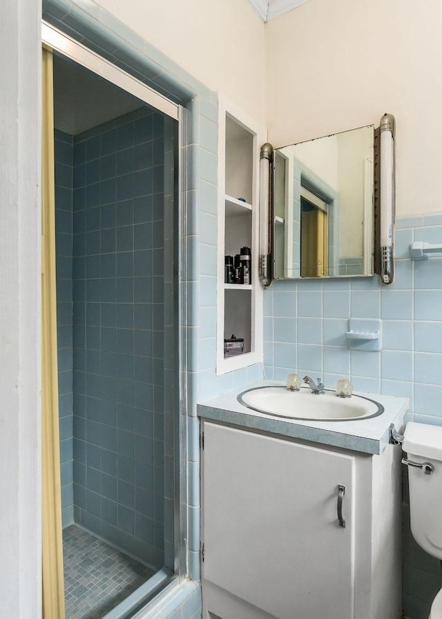 bathroom featuring a tile shower, vanity, tile walls, and toilet