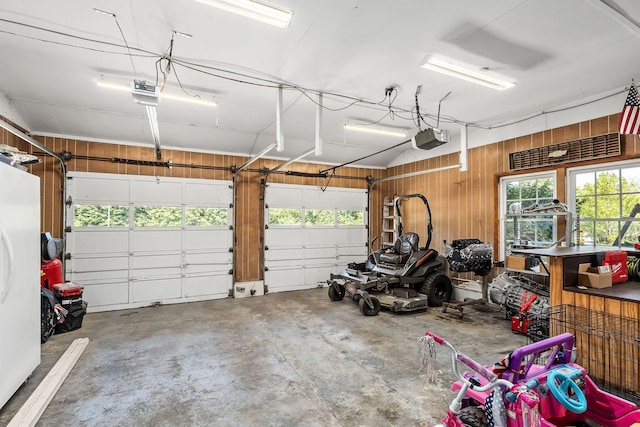 garage featuring wood walls, a garage door opener, and white refrigerator