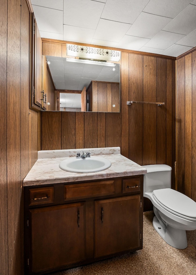 bathroom with vanity, toilet, and wooden walls