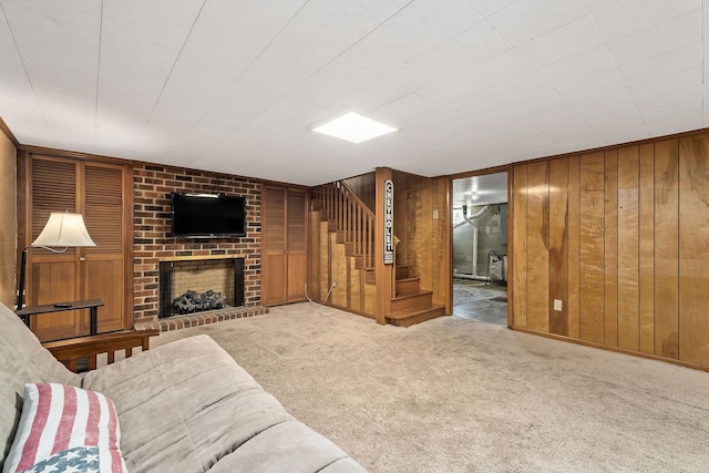 carpeted living room featuring wood walls and a fireplace