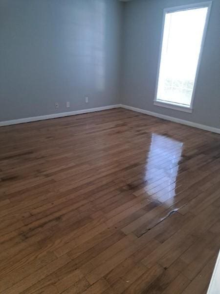 empty room featuring plenty of natural light and dark hardwood / wood-style flooring